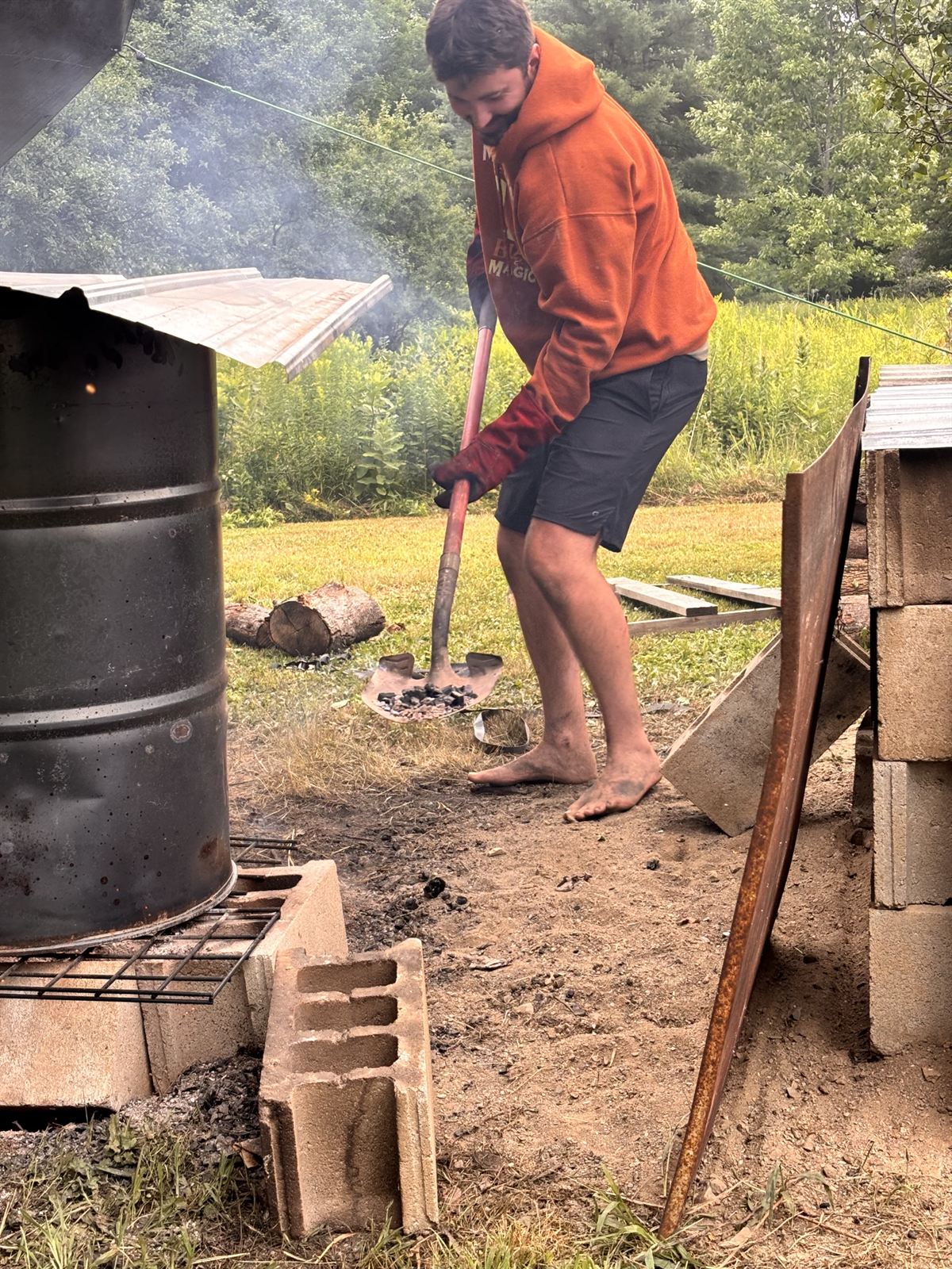 Shoveling coals into the pit at first light with smoke in the air