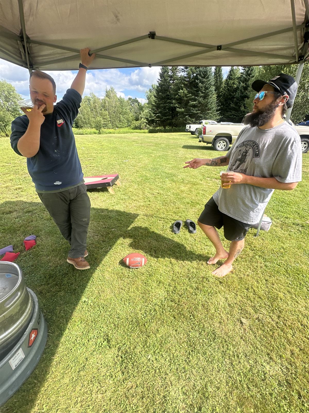 Cornhole on the sunny lawn with the keg on ice nearby
