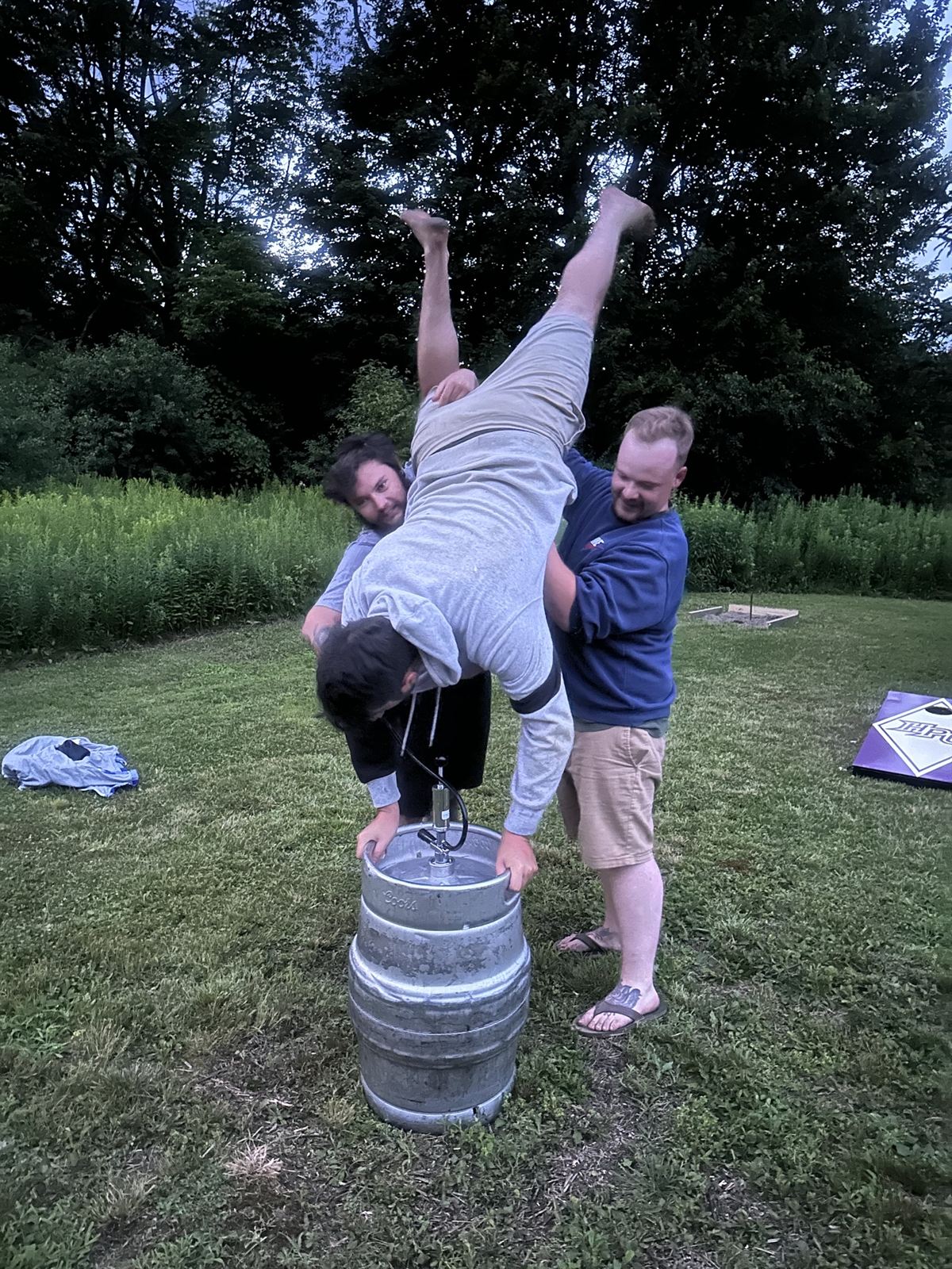 A keg stand on the lawn at dusk