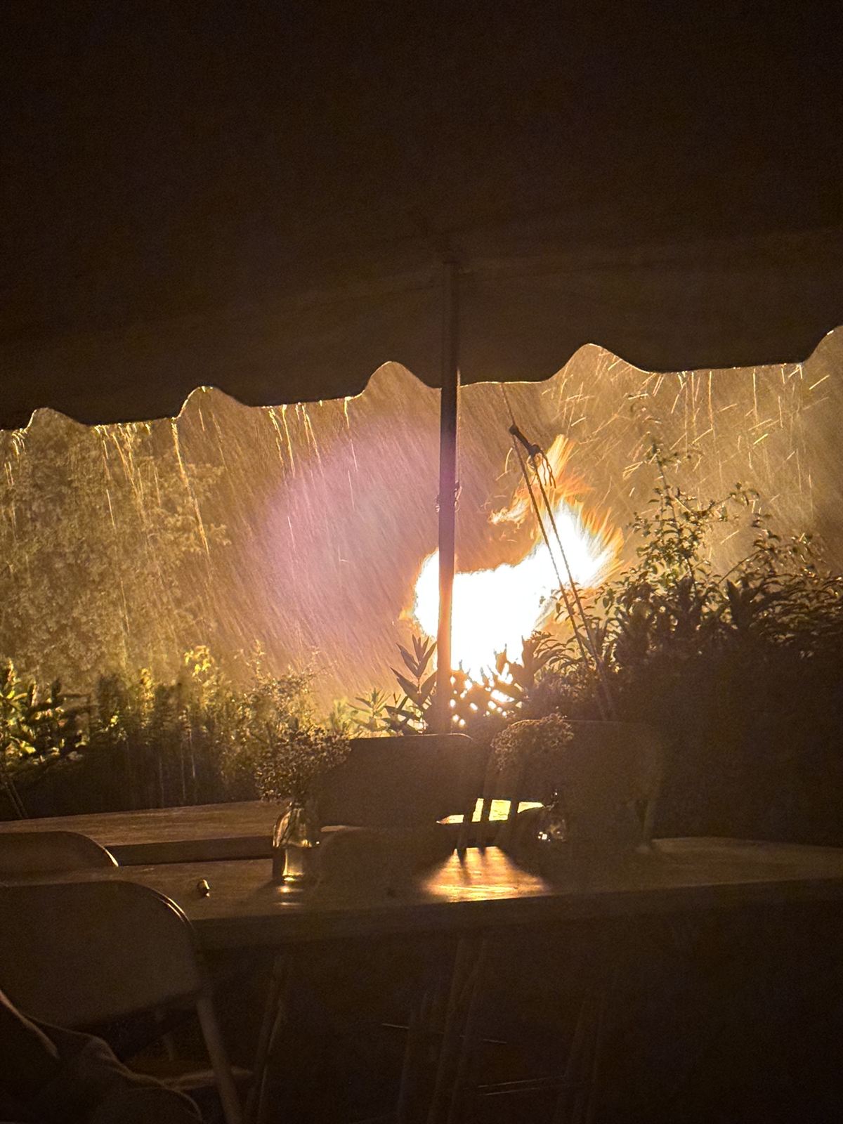 The bonfire burning in the rain, from under the tent